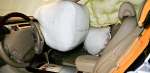 Car interior with multiple deployed airbags, including front and side airbags, indicating a recent collision