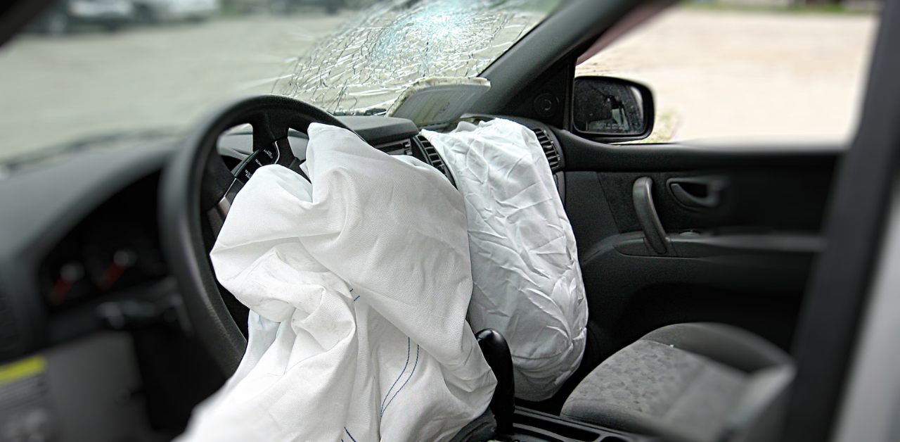 Interior of a car with deployed airbags and a shattered windshield, showing damage after an accident