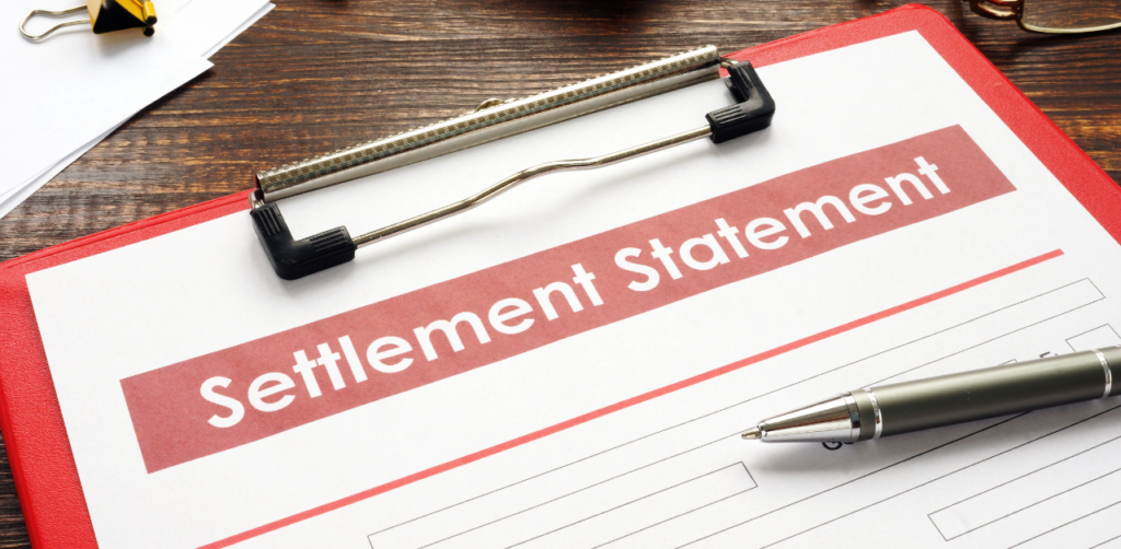 A close-up of a clipboard with a document labeled "Settlement Statement" and a pen resting beside it