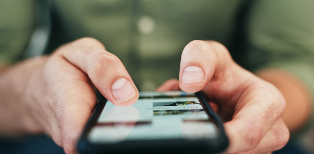 A close-up of a person's hands as they hold and use a smartphone, with fingers tapping on the screen