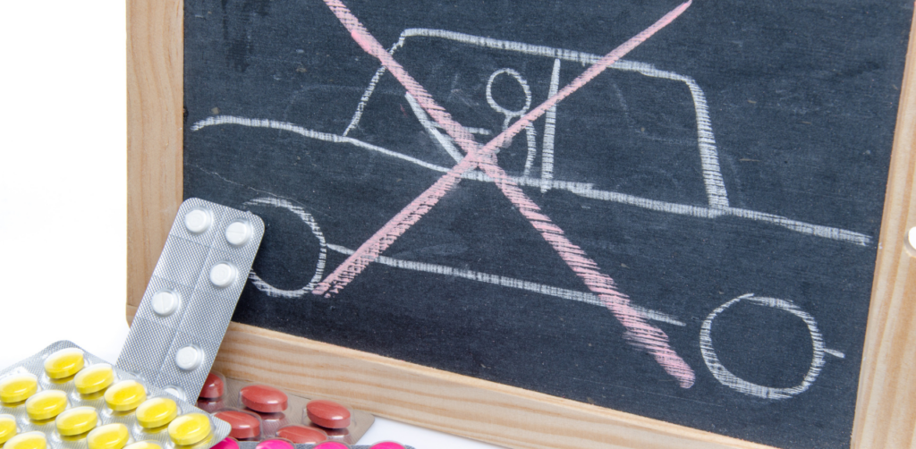 Blackboard drawing of a crossed-out car with pills scattered in front