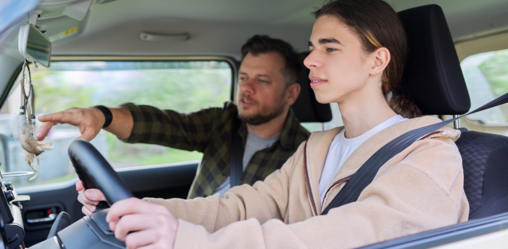 Teen driver at the wheel with an instructor pointing out something inside the car