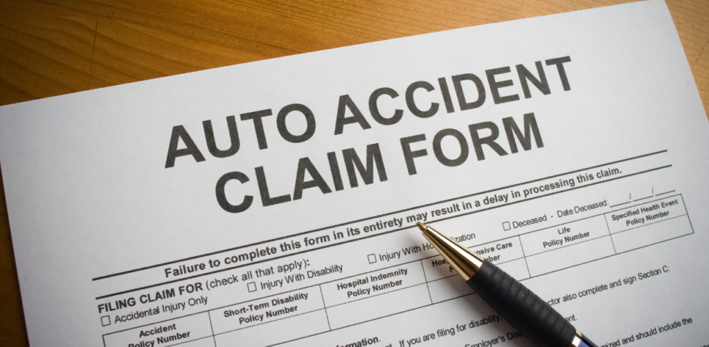 Close-up of an auto accident claim form on a desk with a black and gold pen resting on top