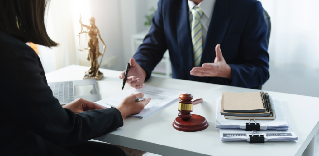 Lawyer and client discussing an auto accident case at a desk with legal documents and a gavel