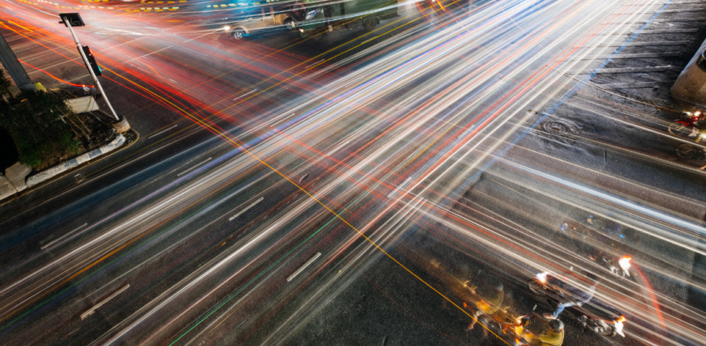 Long-exposure shot of a busy city intersection at night with vibrant light trails from passing traffic