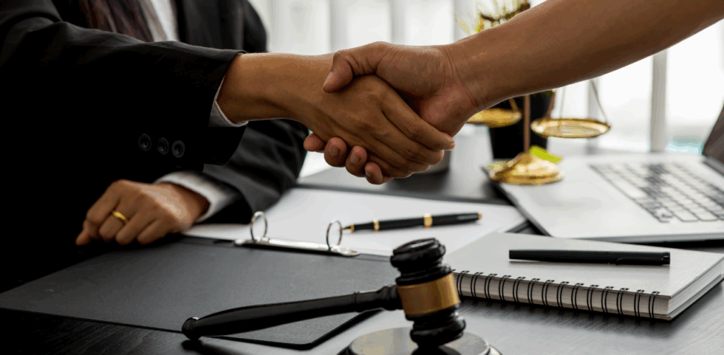 Two people shake hands in a law office, representing legal agreement or settlement reached