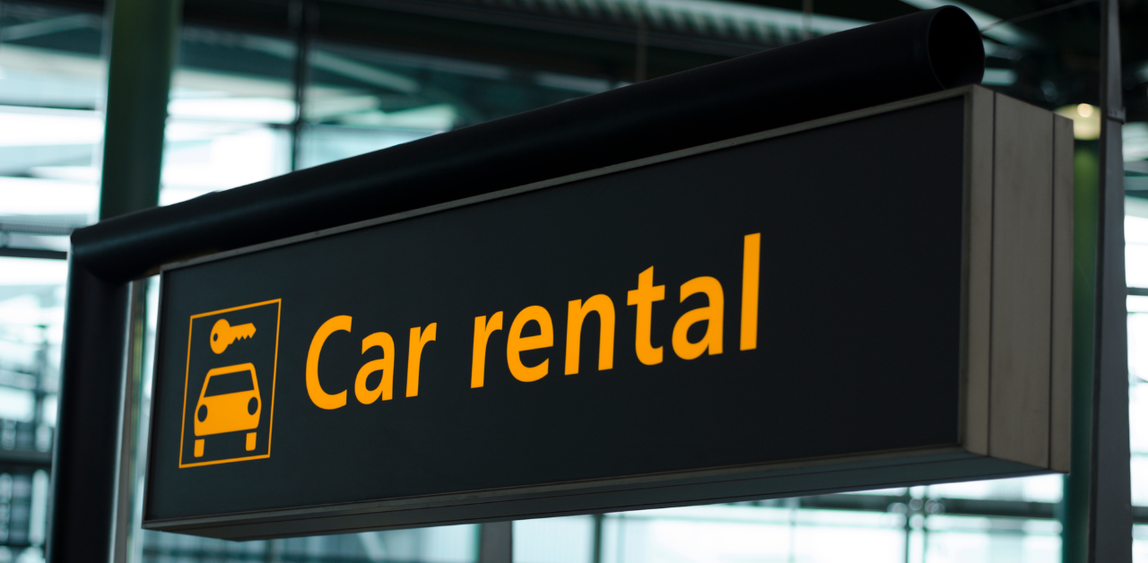 A Car rental sign with a car and key icon, commonly seen at airports or car rental facilities