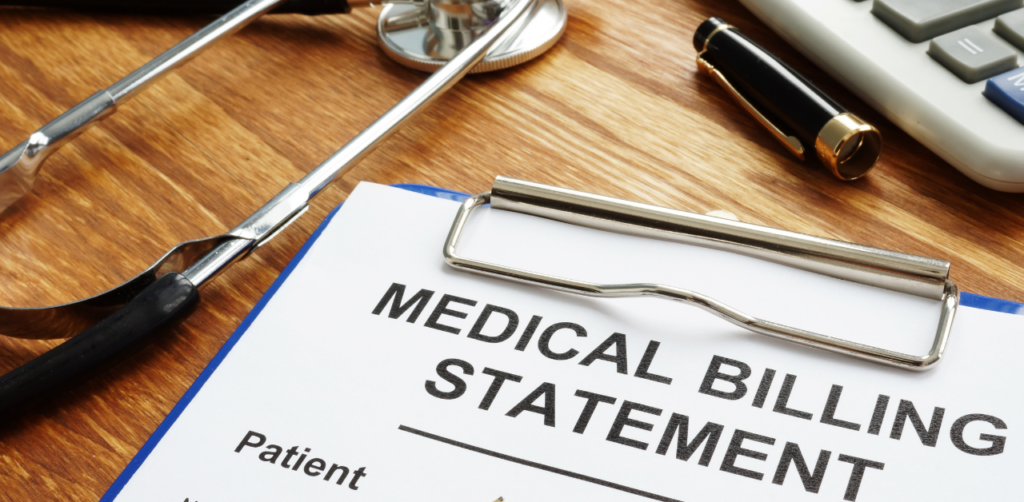 A close-up of a medical billing statement on a clipboard, surrounded by a stethoscope, pen, and calculator on a wooden desk