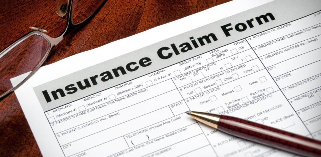 A close-up of an insurance claim form on a desk with a pair of glasses and a pen