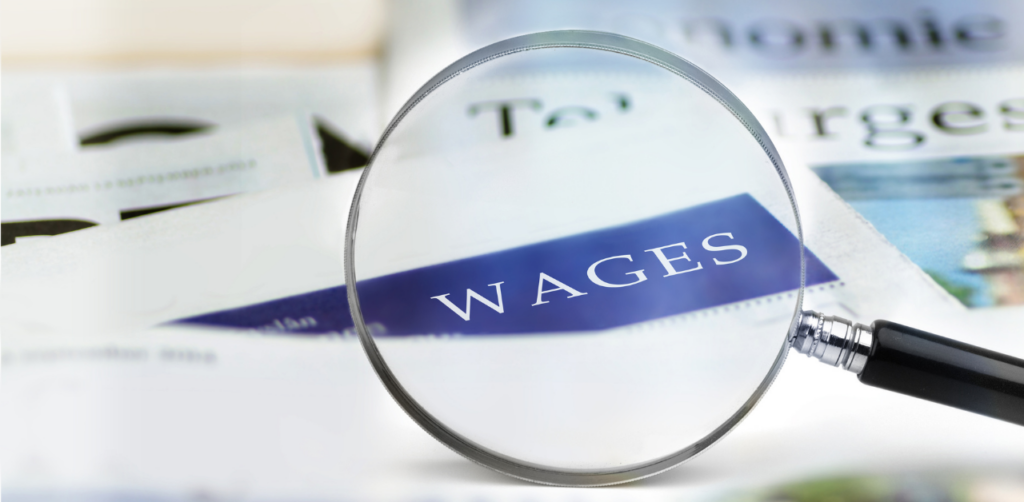 The word "wages" magnified through a glass lens, over a blurred background of documents