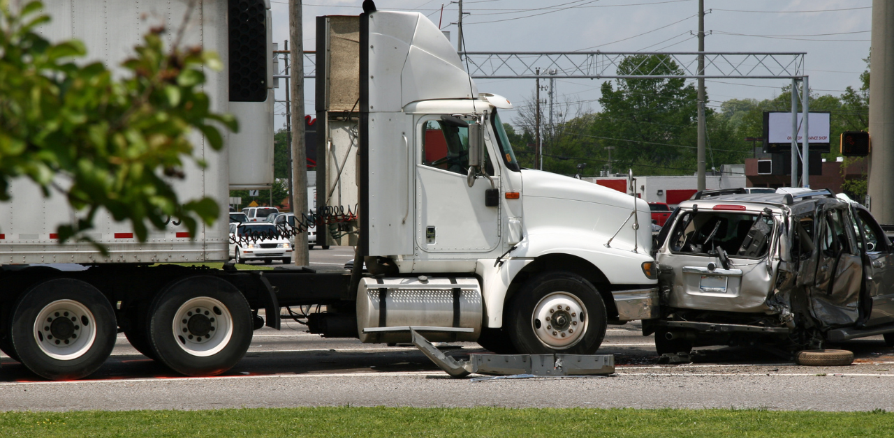 A large white semi-truck involved in a collision with a severely damaged SUV at an intersection