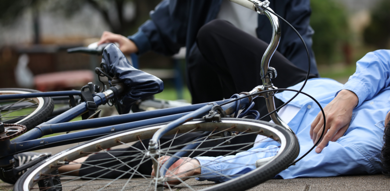 A person lying on the ground next to a fallen bicycle, suggesting a potential accident or injury