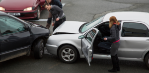 Two cars involved in a minor collision, with people standing around inspecting the damage