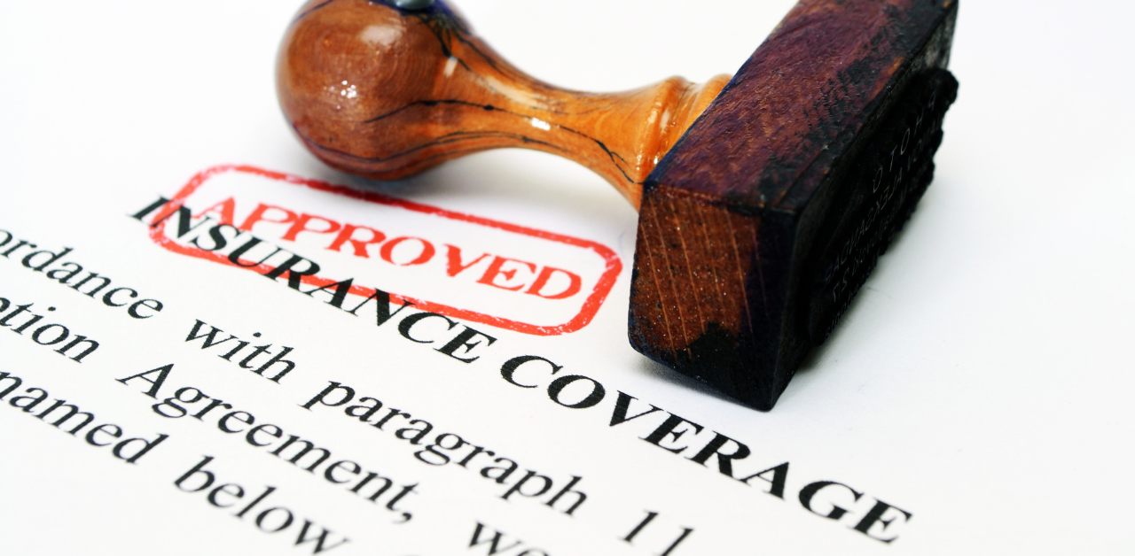 A wooden stamp marked APPROVED on a document about insurance coverage