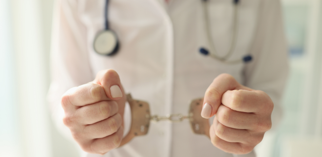 Close-up of a doctor wearing a white coat and holding handcuffs, symbolizing legal or ethical challenges in the medical profession