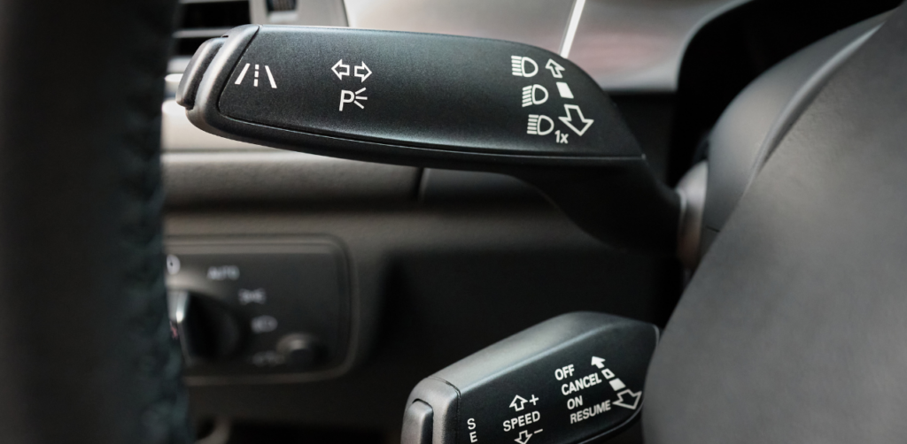 Close-up of car controls showing symbols for headlights, turn signals, and cruise control functions