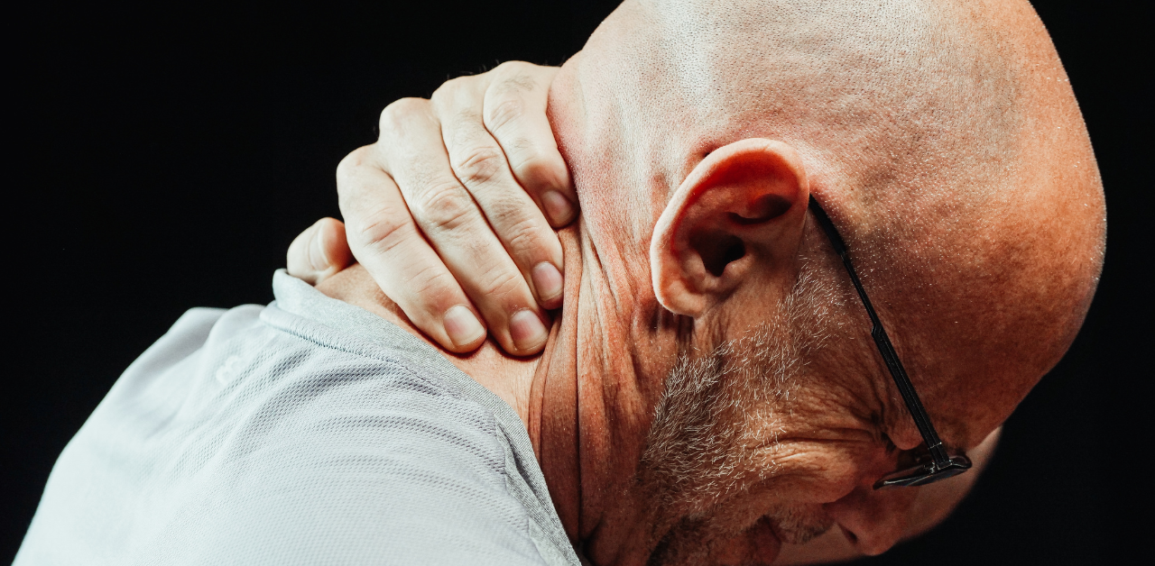 Bald man holding the back of his neck, appearing to be in pain