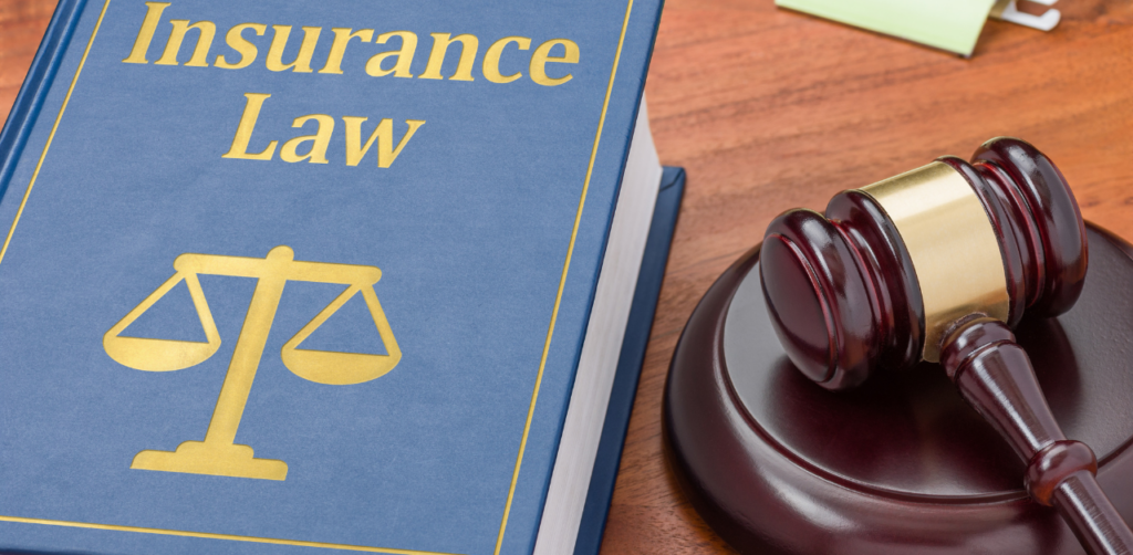 Book titled Insurance Law next to a gavel on a wooden desk