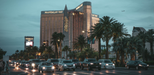 Evening traffic on the Las Vegas Strip, with Mandalay Bay and Luxor hotels illuminated in the background, surrounded by palm trees