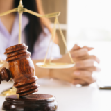 Gavel and scales of justice on a desk, with a person sitting in the background
