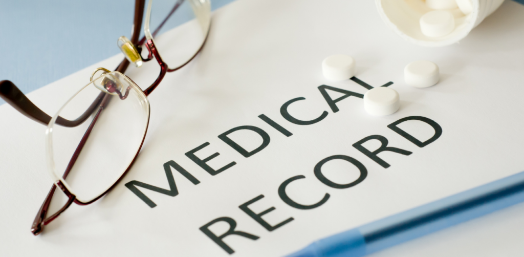 Pair of eyeglasses and white pills on a document labeled Medical Record