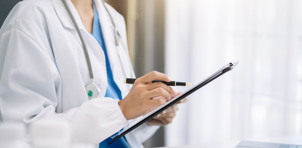 Doctor in a white coat writing on a clipboard
