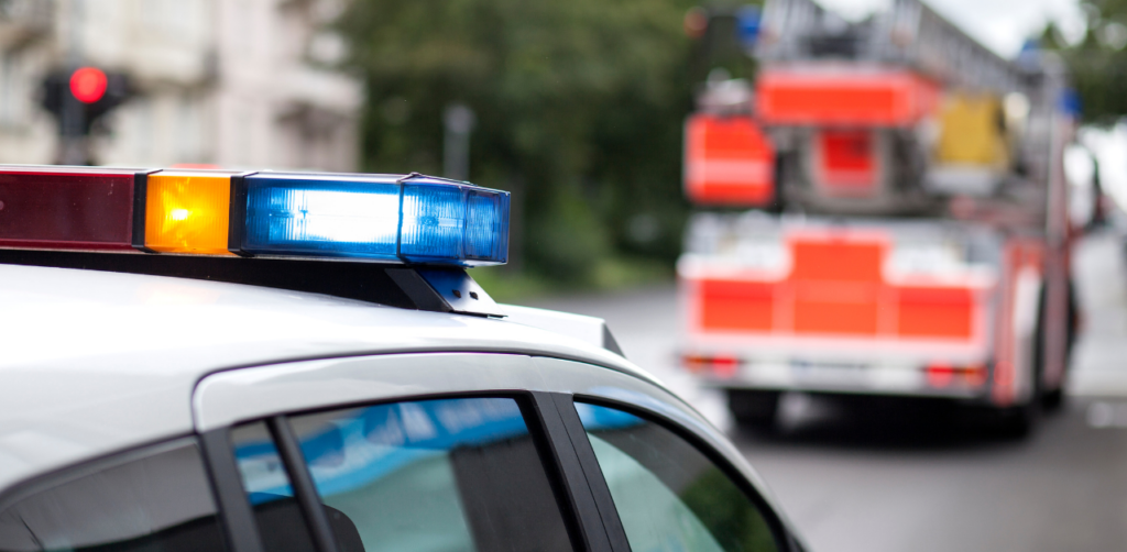 Police car with flashing lights, fire truck in background