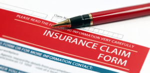 Red and white insurance claim form with a red pen placed on top