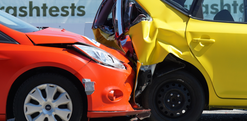 Red car rear-ended by a yellow car in a crash test, showing severe damage to both vehicles