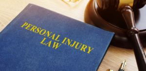 Blue hardcover book titled Personal Injury Law next to a wooden gavel and gold pen on a desk