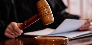 Close-up of a judge holding a gavel above a sound block with legal documents visible in the background