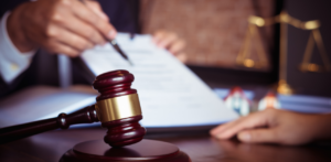 Lawyer reviewing legal documents with client at desk, with gavel and justice scales symbolizing legal counsel