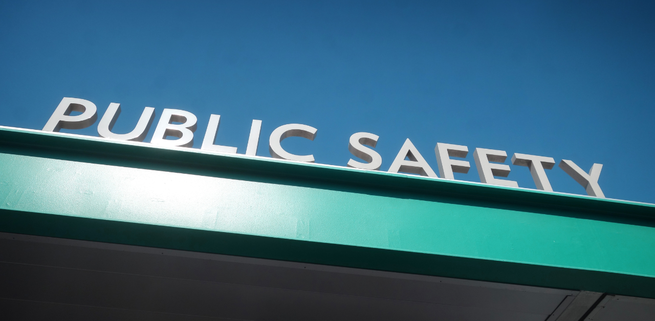White letters spelling Public Safety on a teal building facade under a clear blue sky