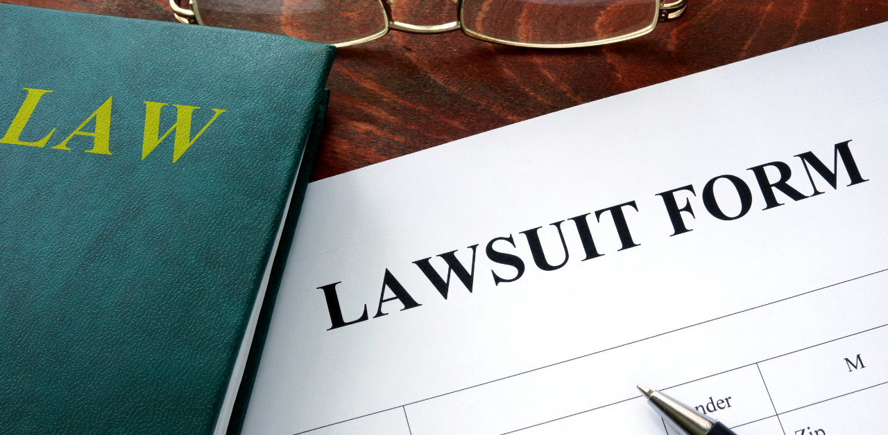 Lawsuit form on desk beside law book and pen, symbolizing the start of legal action or civil litigation