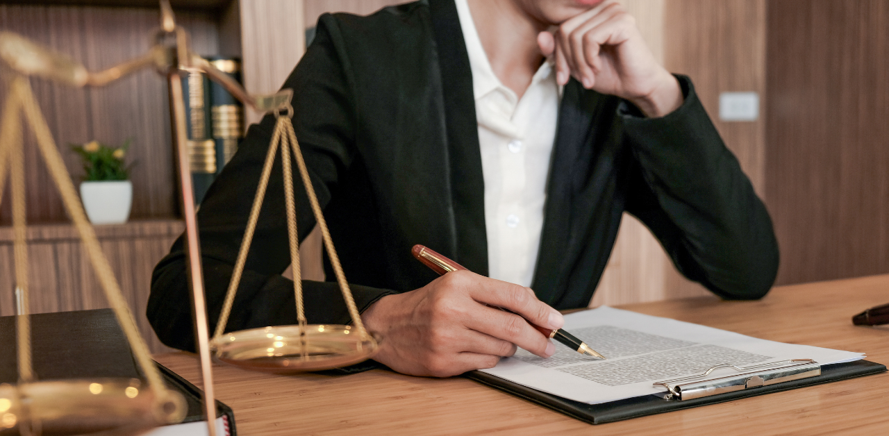 Lawyer reviewing legal documents at a desk with scales of justice in the foreground