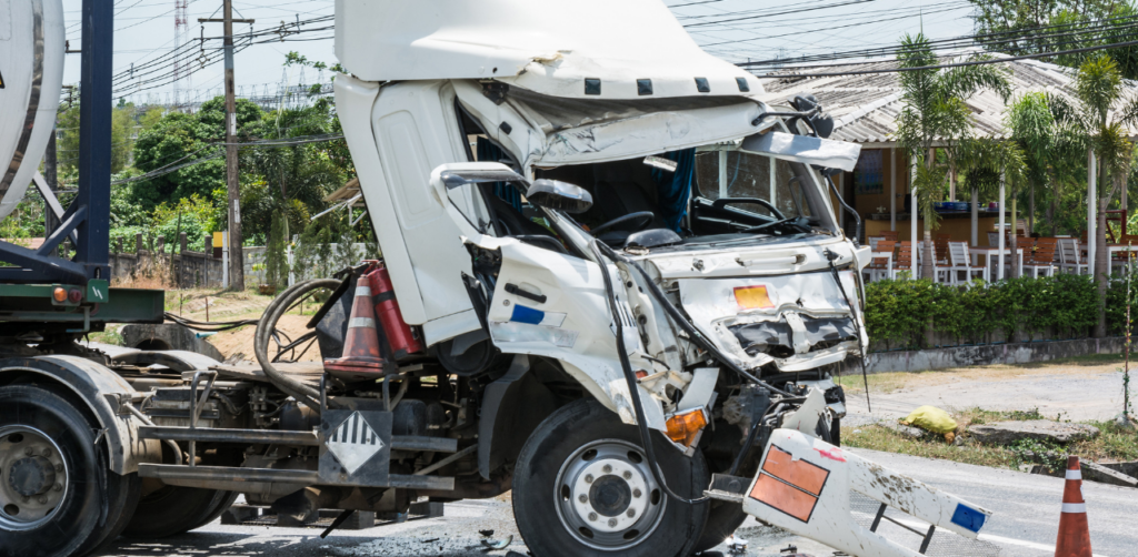 Severely damaged white semi-truck at an accident scene, showing front-end impact and roadside debris