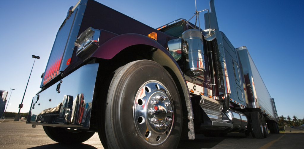 Low-angle view of a shiny semi-truck parked under a clear blue sky