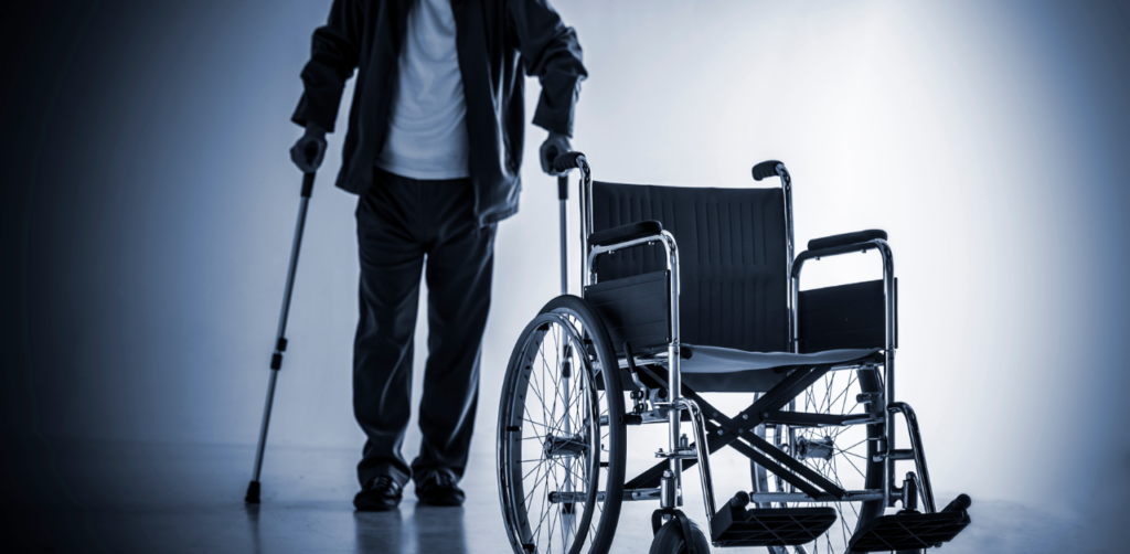 Person with cane stands near empty wheelchair, suggesting recovery or mobility disability