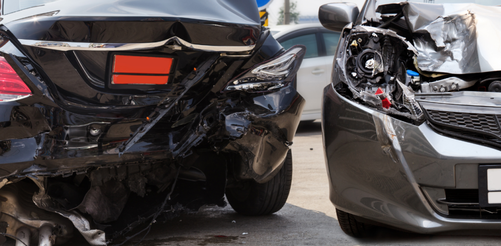Two heavily damaged cars after a rear-end collision, showing crumpled bumpers and smashed headlights