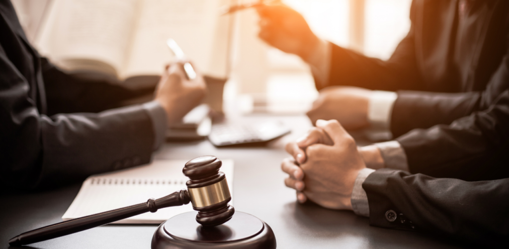 Close-up of a legal meeting with people in suits discussing documents beside a gavel on the table