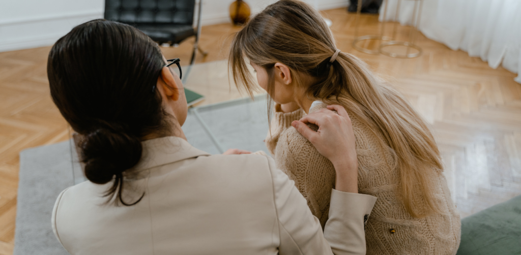 Therapist comforts distressed woman during emotional support session in counseling office