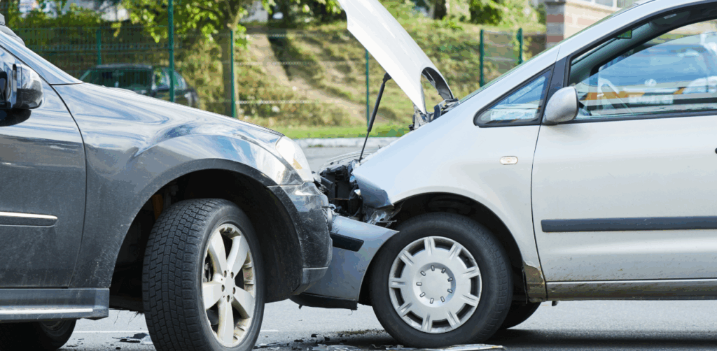 A silver car with its hood up has rear-ended a black SUV in a minor street collision