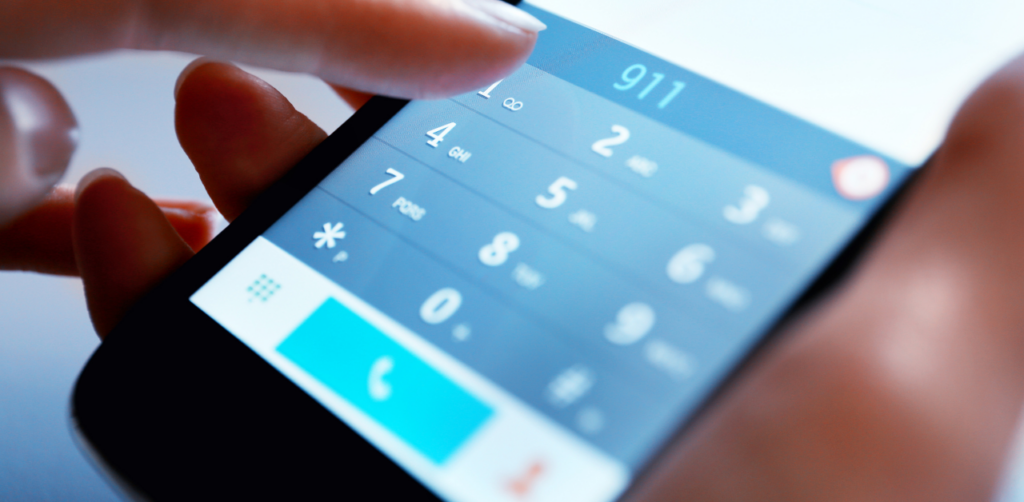 Person dialing 911 on a smartphone in an emergency situation