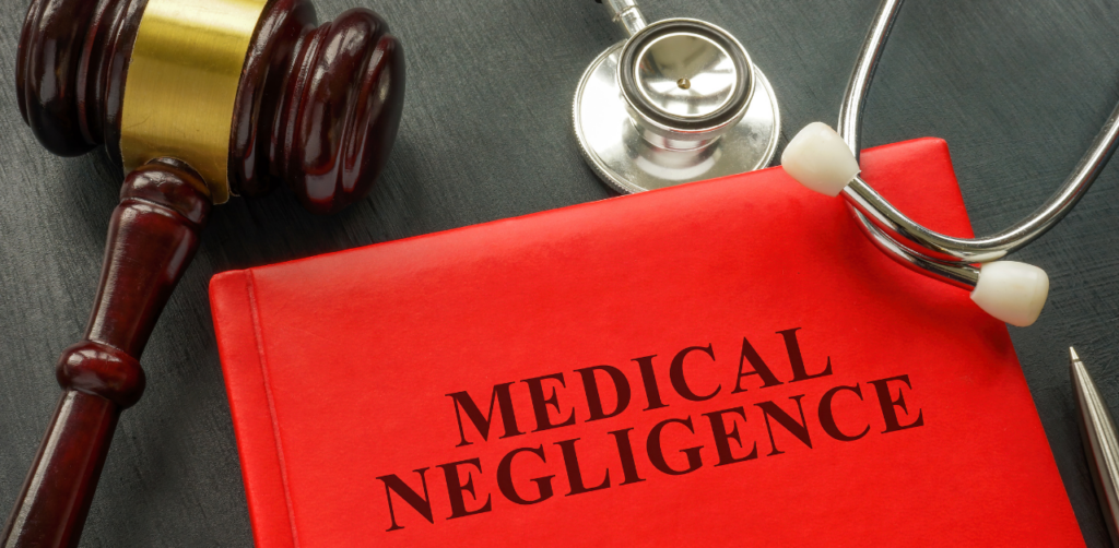 Red book titled “Medical Negligence” placed beside a judge’s gavel and a stethoscope
