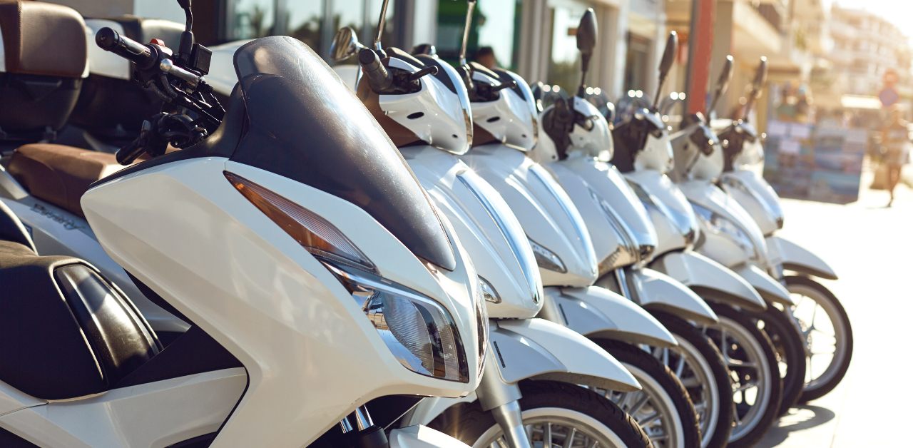 Row of parked white scooters lined up outside on a sunny day