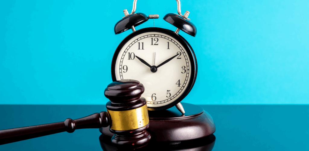 Black alarm clock and judge’s gavel on a glossy surface, symbolizing a legal deadline