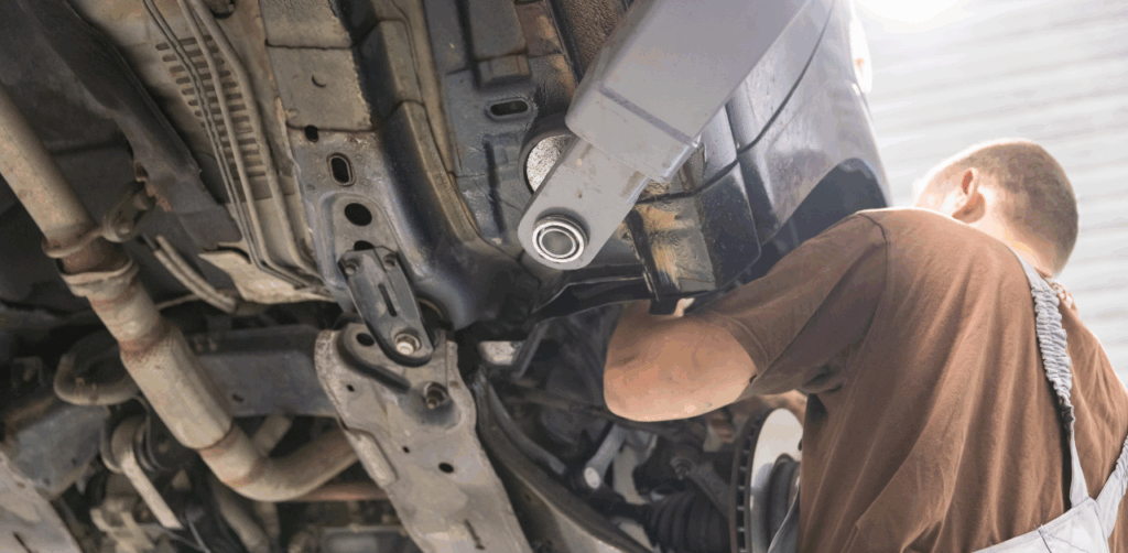 Mechanic works underneath a raised vehicle, inspecting its undercarriage