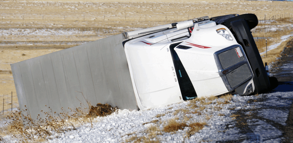 Overturned semi-truck on icy road highlights winter truck driver safety hazards