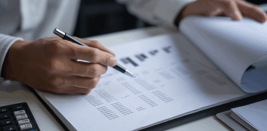 Person reviews financial or legal documents with a pen and calculator on the desk