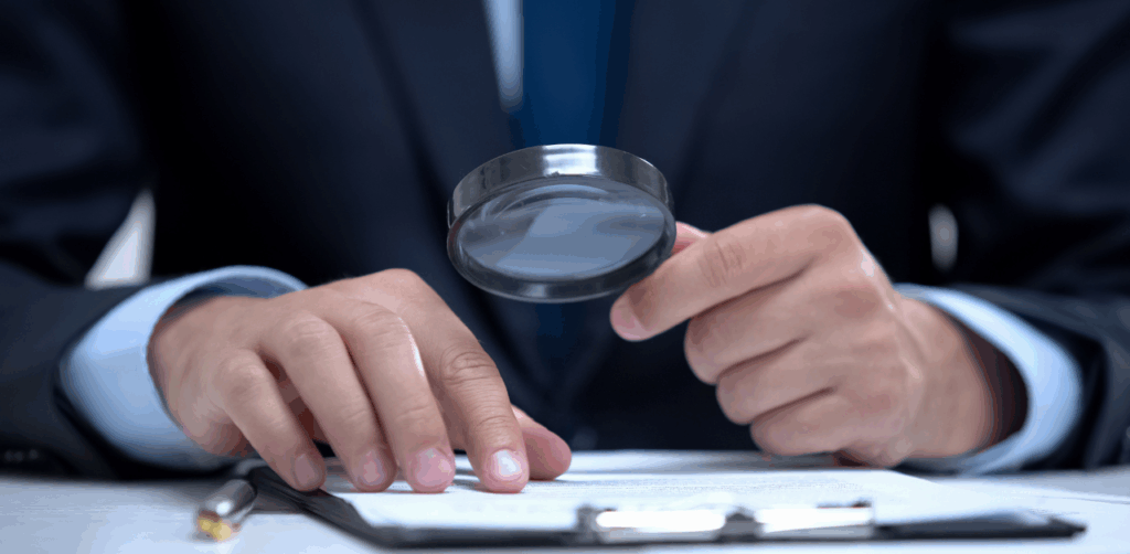 Man in suit examines document with magnifying glass, symbolizing a truck accident investigation